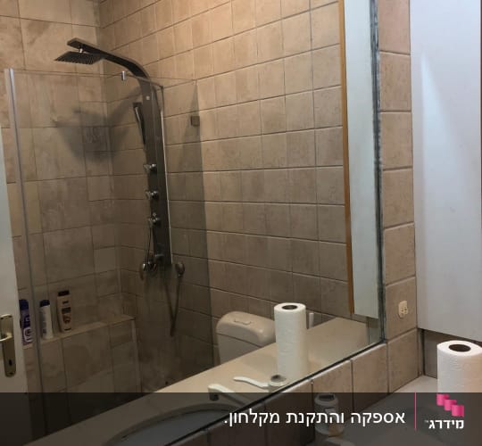מקלחון זכוכית מותקן המשתקף במראת חדר רחצה
